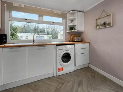 a kitchen with a washing machine and a window at Lisset in Newton Stewart