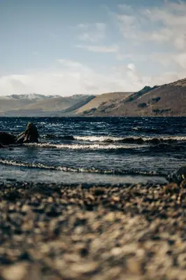 a view of a beach with mountains in the background at Loch Earn leisure park in Saint Fillans