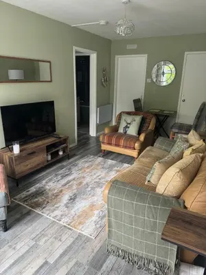 a living room with a couch and a flat screen tv at Loch Lomond Riverside Apartments B in Balloch
