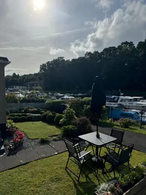 a table and chairs in a yard with a view at Loch Lomond Riverside Apartments B in Balloch