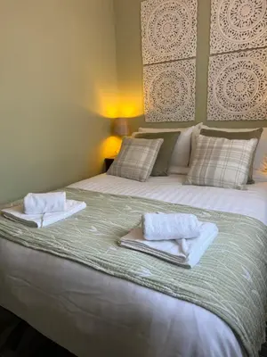 a bedroom with a large bed with towels on it at Loch Lomond Riverside Apartments B in Balloch