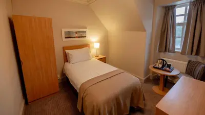 a hotel room with a bed and a table and a window at The Tarbet Hotel in Tarbet