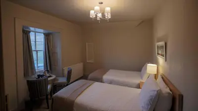 a hotel room with two beds and a table and a chair at The Tarbet Hotel in Tarbet