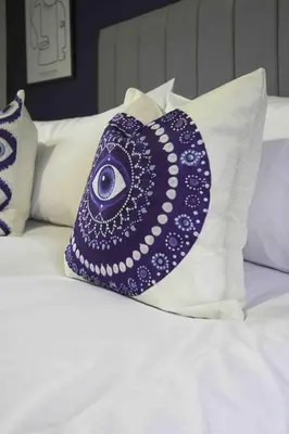 a purple pillow with an eye on top of a bed at Cochran House in Bathgate