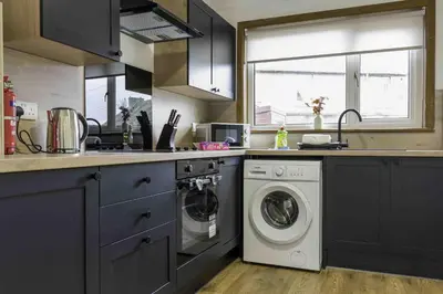 a kitchen with a washing machine and a washer at Cochran House in Bathgate