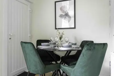 a dining room with a table with green chairs at Scotia House in Larkhall