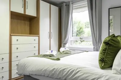 a bedroom with a white bed with a window at Pentland House in Bathgate