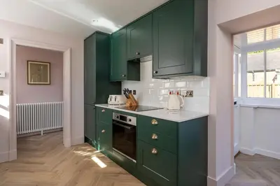 a green kitchen with green cabinets and a window at Queensberry Cottage in Thornhill