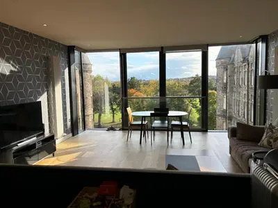 a living room with a table and a large window at Stunning park view Quartermile apartment close proximity to Castle University in Edinburgh