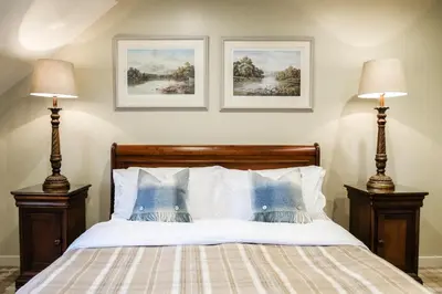 a bedroom with a bed with two lamps at Luss Cottages at Loch Lomond Arms Hotel in Luss