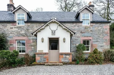 an old stone house with a front door at Luss Cottages at Loch Lomond Arms Hotel in Luss