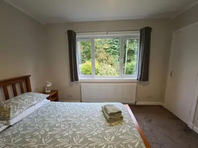 a bedroom with a bed and a large window at Lademill Cottage in Aberfeldy