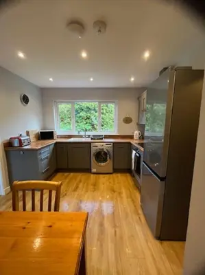 a kitchen with a refrigerator and a table in it at Lademill Cottage in Aberfeldy