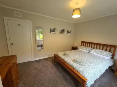 a bedroom with a bed and a mirror and a window at Lademill Cottage in Aberfeldy