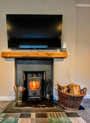 a living room with a fireplace with a television above it at Lademill Cottage in Aberfeldy