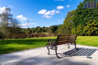 a bench sitting on a sidewalk in a park at Large Family Home with Hot Tub or Jacuzzi, Log Burner in Bearsden