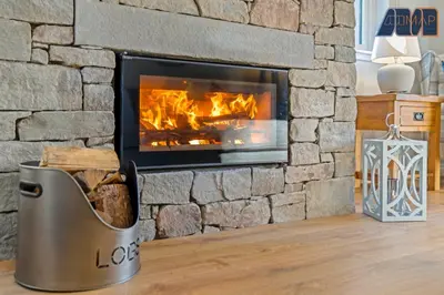 a stone fireplace with a metal trash can in front of it at Large Family Home with Hot Tub or Jacuzzi, Log Burner in Bearsden