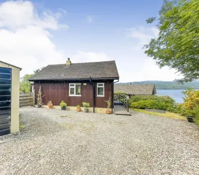 a small red house with a gravel driveway at Picturesque beauty of Strachur in Strachur