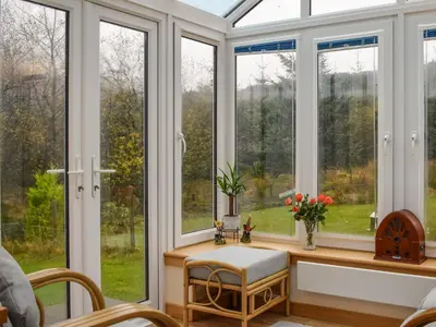 a conservatory with windows and a table with a chair at Pine Cottage in Killin