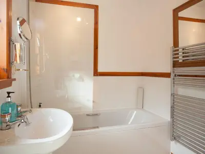 a white bathroom with a tub and a sink at Aonach Cottage - Uk41932 in Glencoe