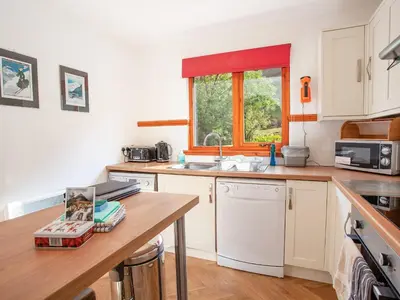 a kitchen with white cabinets and a sink and a window at Aonach Cottage - Uk41932 in Glencoe