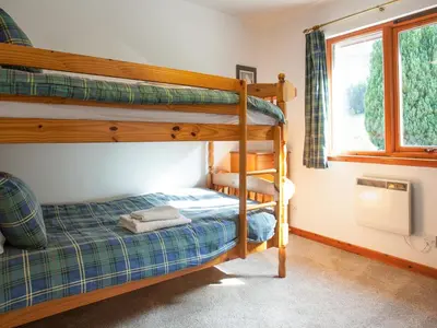 a bedroom with two bunk beds and a window at Aonach Cottage - Uk41932 in Glencoe