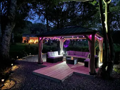 a gazebo with a couch on a deck at night at The Coach House Knipoch in Oban