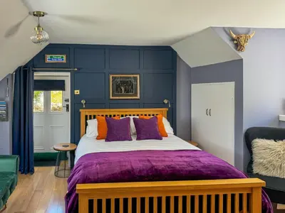 a bedroom with a large bed with purple walls at The Coach House Knipoch in Oban