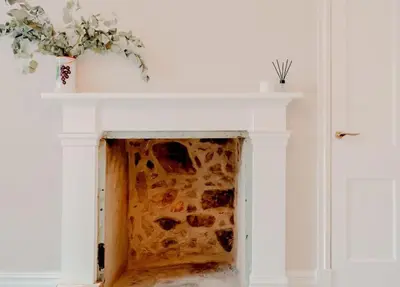 a fireplace with a white mantle with a plant on it at Number Twenty Seven luxury apartment, Aberdour, Fife in Aberdour