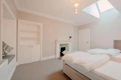 a white bedroom with two beds and a fireplace at Number Twenty Seven luxury apartment, Aberdour, Fife in Aberdour
