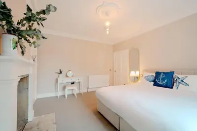 a white bedroom with a bed and a desk at Number Twenty Seven luxury apartment, Aberdour, Fife in Aberdour