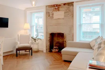 a living room with a white couch and a fireplace at Number Twenty Seven luxury apartment, Aberdour, Fife in Aberdour