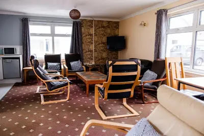 a living room with chairs and a table and a tv at Lochranza Centre CIC in Lochranza