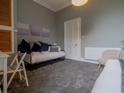 a bedroom with a bed with blue pillows and a chair at Spacious Hillhead Haven - Pass the Keys in Glasgow