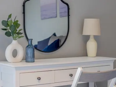 a mirror on top of a white dresser with a vase and a lamp at Spacious Hillhead Haven - Pass the Keys in Glasgow