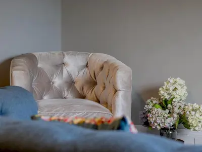a living room with a leather chair and flowers at The Blue Nile Hillhead - Pass the Keys in Glasgow