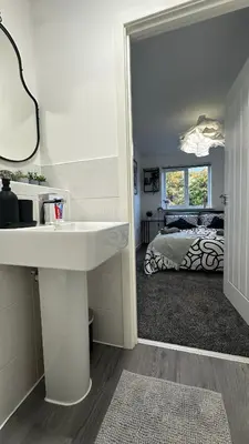 a bathroom with a sink and a mirror and a bed at Newbuild Riverview 3BDR House near Glasgow in Dalmuir