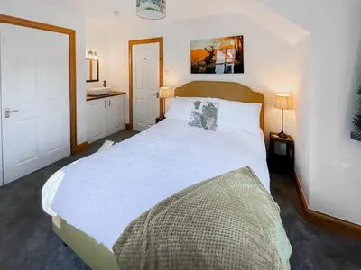 a bedroom with a large white bed with two pillows at Fin Glen in Killin