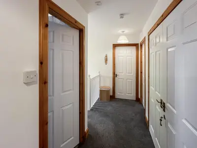 a hallway with two white doors and a toilet at Fin Glen in Killin