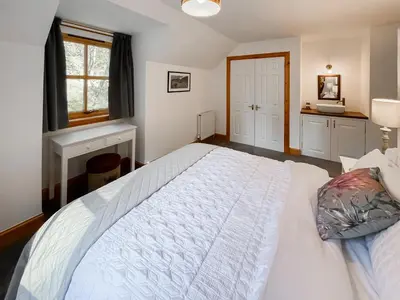 a bedroom with a white bed and a window at Fin Glen in Killin