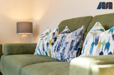 a green couch with blue and white pillows on it at Elegant 2Bed Sleeps 4 With Parking in Paisley