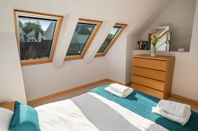 a bedroom with a bed and two windows at Stunning Sea Views - Luxury 4BR Beach House in Oban