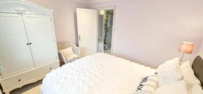 a white bedroom with a bed and a chair at Boghead Cottage The West Wing in Bathgate