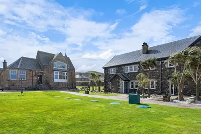 a large house with a green lawn in front of it at Ugadale Cottages in Machrihanish
