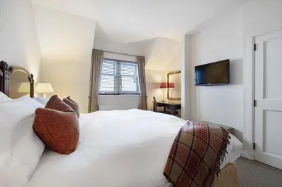 a bedroom with a white bed with a television on the wall at Ugadale Cottages in Machrihanish