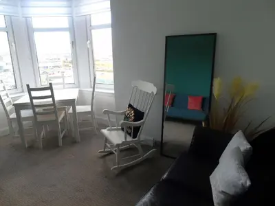 a living room with a table and chairs and a mirror at Snug - Grian-aig Apartment in Greenock