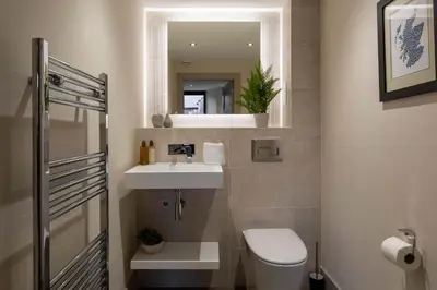 a bathroom with a sink and a toilet and a mirror at Arran Shores Luxury Shorefront Apartment 2 in Lamlash