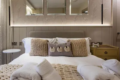 a bedroom with a bed with pillows and a mirror at Arran Shores Luxury Shorefront Apartment 4 in Lamlash