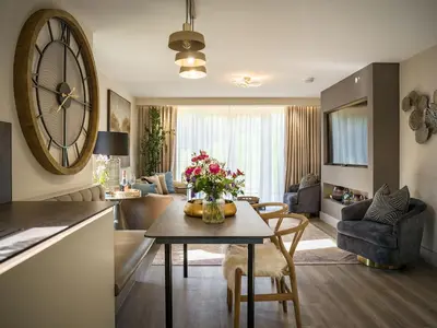 a living room with a table and a large clock on the wall at Arran Shores Luxury Shorefront Garden Terrace Apartment 6 in Lamlash