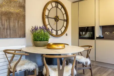 a table with two chairs and a clock on the wall at Arran Shores Luxury Shorefront Apartment 14 in Lamlash